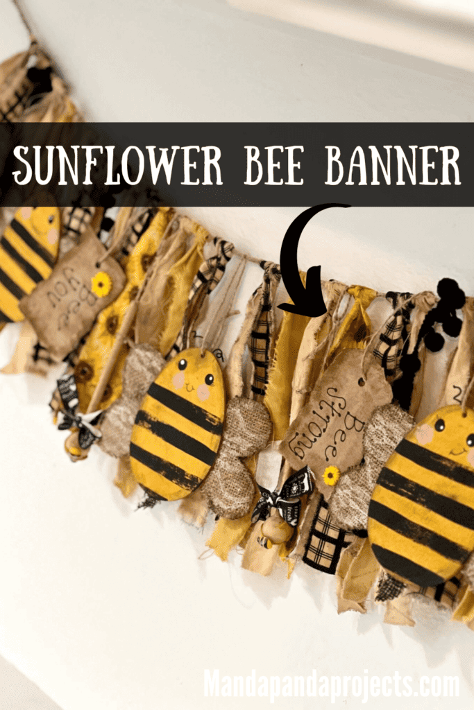 Bumblebee Sunflower Swag Banner with yellow, black, and white coordinating fabric, Dollar Tree Easter Egg bees, kraft paper hangtags that say "Bee kind", "bee grateful", "bee you", and "Bee humble", with honey dippers, small sunflowers, and small bee embellishments, hanging along the wall to decorate a home for spring or summer. The swag is old and grungy and distressed.