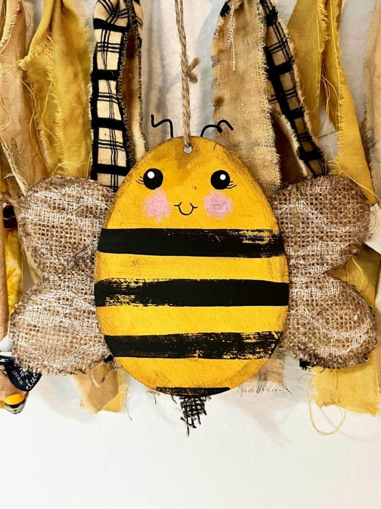 Close up of the easter egg bumblebee with distressed black stripes, lacey burlap wings, cute round eyes and rosy pink cheeks.