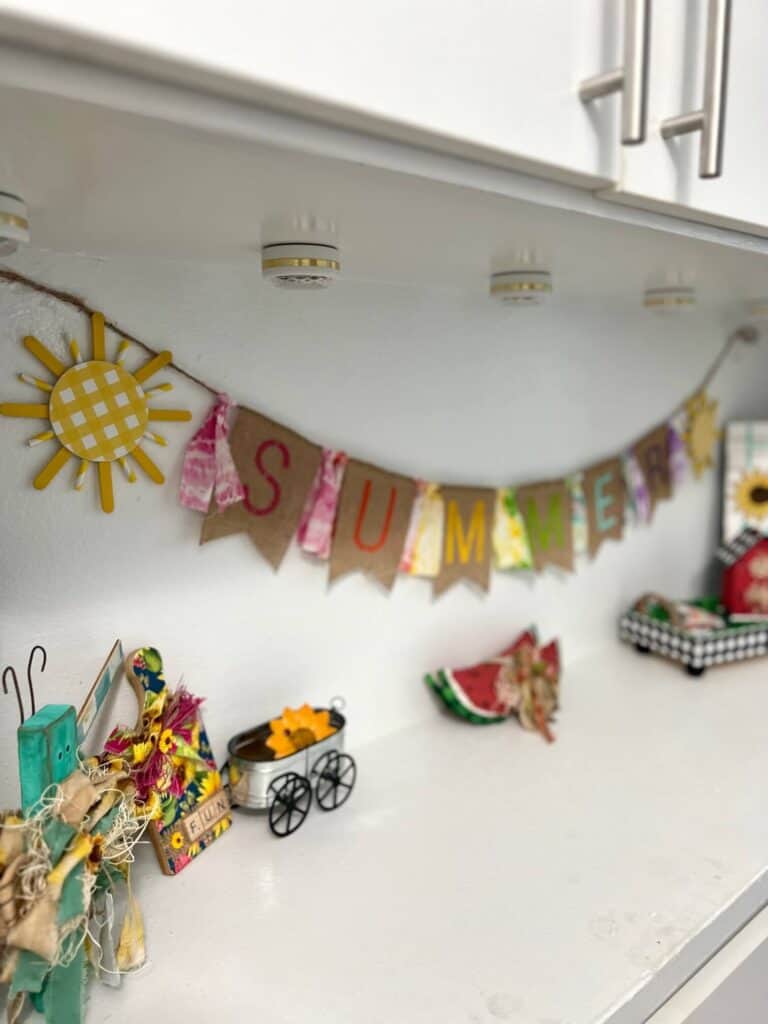 A side portrait of the Summer banner with rainbow colored letters and a butterfly decor and watermelon under it.