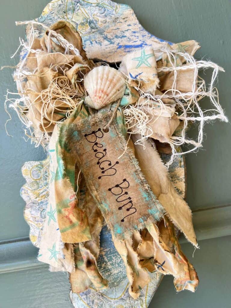 A big messy fabric bow on the seahorse neck with a seashell in the center and a kraft paper hangtag that says "Beach Bum".
