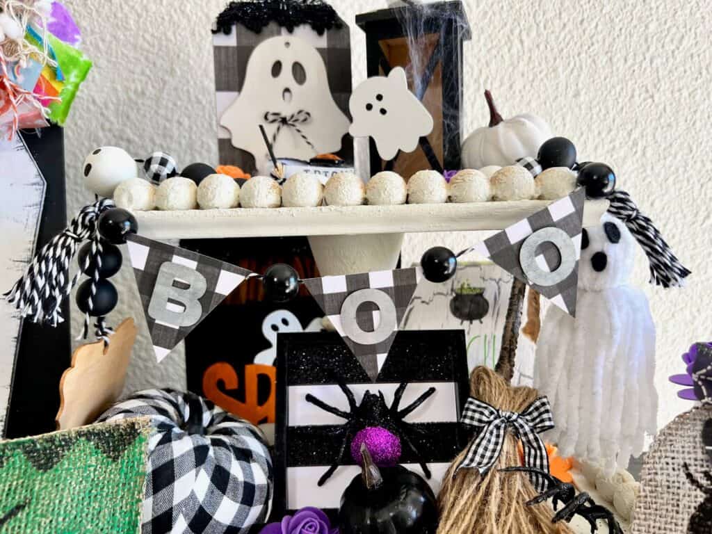 Mini black and white buffalo check BOO banner with tassels on each end, hanging on the top tier of the tray.