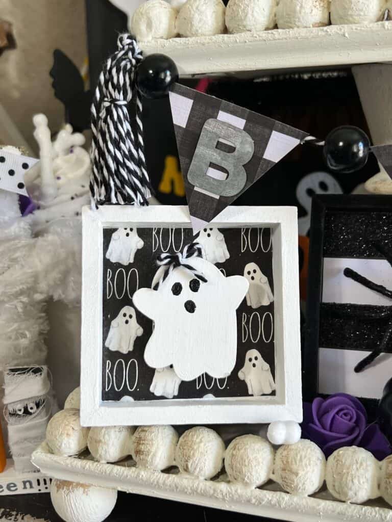 A mini white ghost frame with BOO napkin in the background.