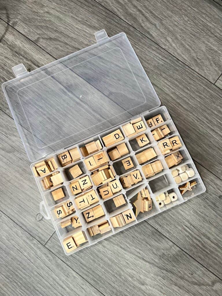 A plastic jewelry organizer filled with scrabble tile letters organized by the letter.