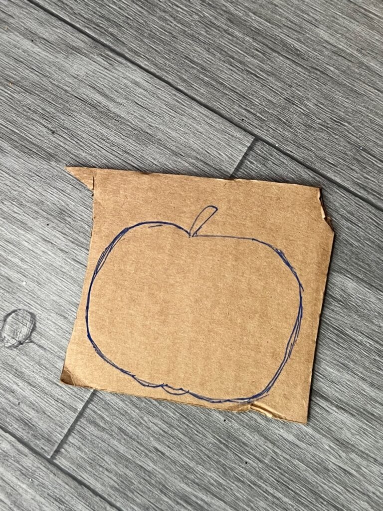 A small piece of cardboard with a pumpkin drawn on it in blue pen.