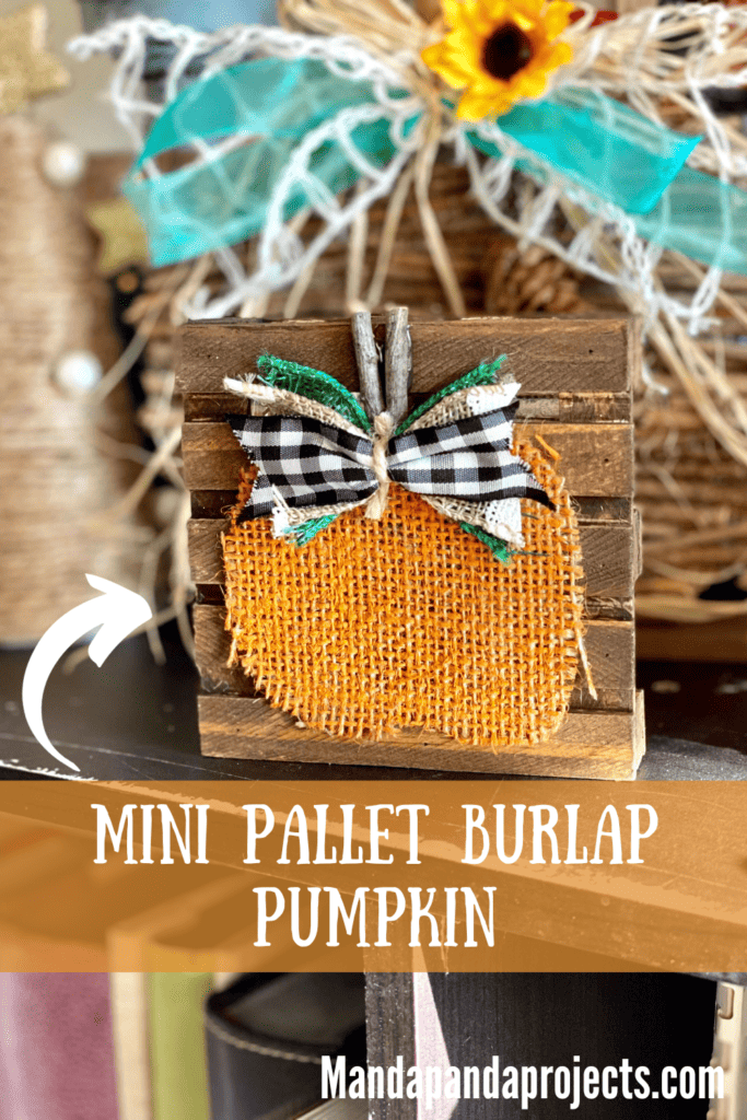 Mini Pallet Burlap Pumpkin with orange painted burlap, a stick stem, and a buffalo check bow on a mini dollar tree pallet that is stained brown with Antique wax.