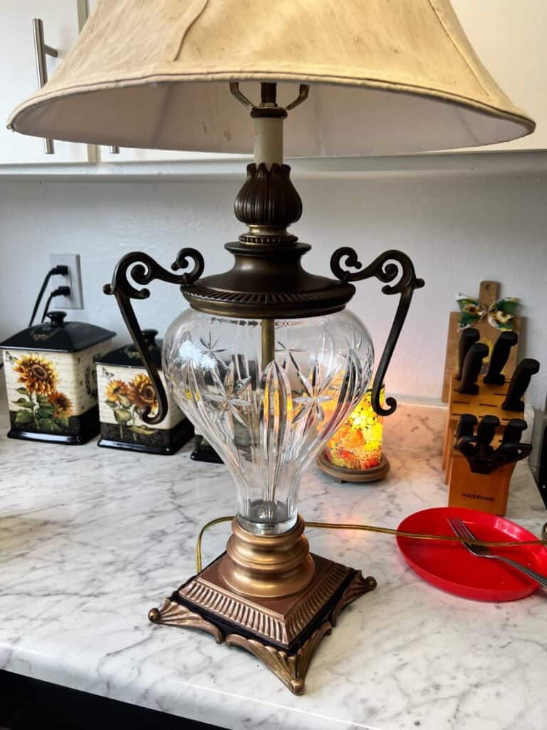 The top brass portion of the lamp tarnished and black, and the bottom portion of the lamp completely restored back to its natural brass color.