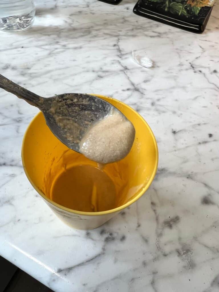 A thick paste of vinegar, salt, and flour on a spoon in a yellow cup.