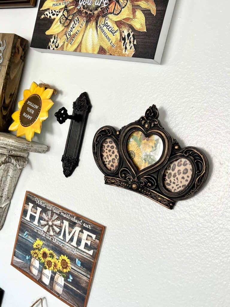 Thrift store crown makeover with gold and black, and leopard print and sunflower inside the frame, hanging on the wall next to an old vintage doorknob.