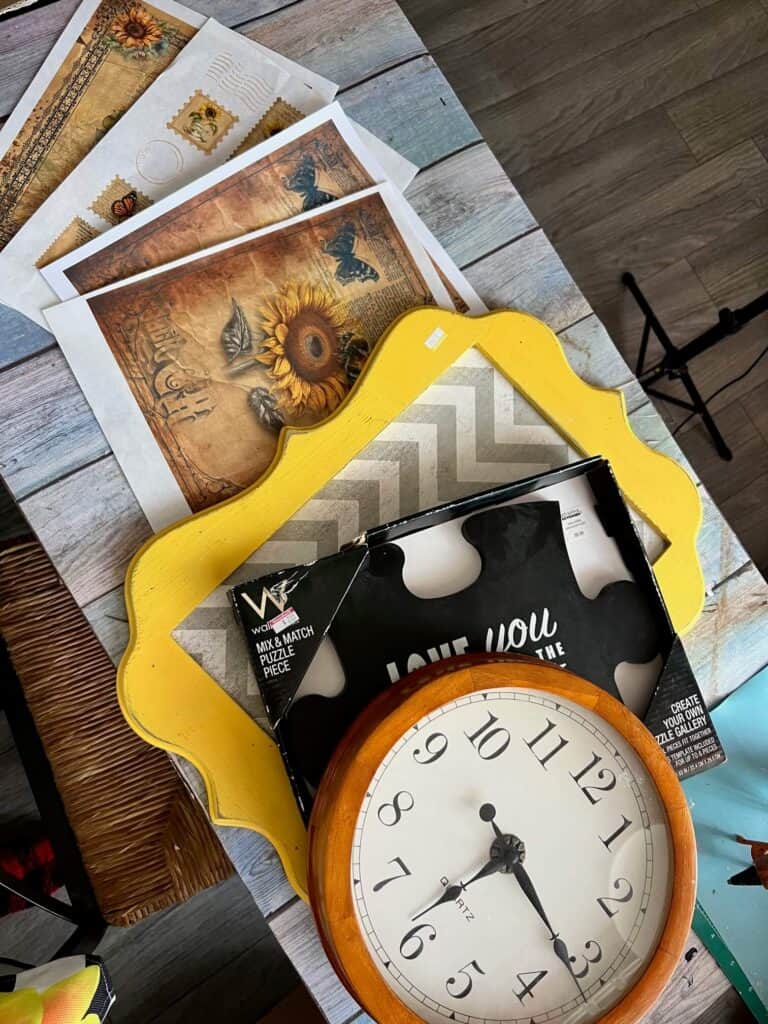 4 sunflower rice paper prints, a yellow large frame, a puzzle piece frame, and the generic clock sitting on a desk all laid out.