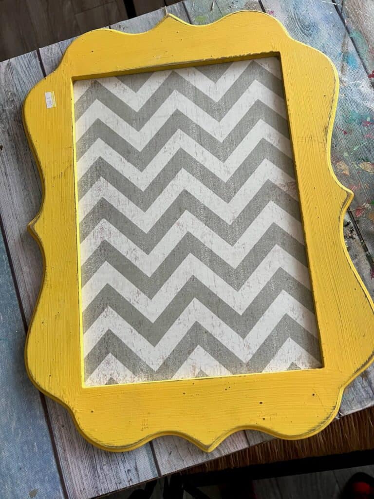 The thrifted framed sign before it was made over, with the yellow outer frame, and grey and white chevron pattern background.