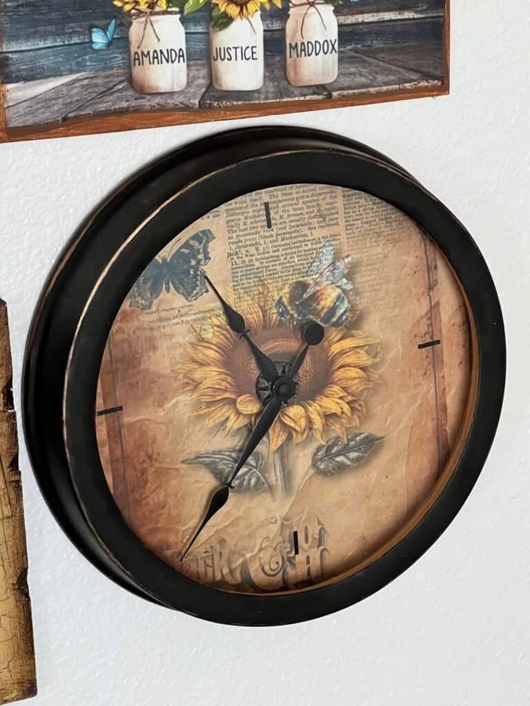 Thrift Store Clock Makeover with a Sunflower vintage rice paper face with a small bee and butterfly, black outer rim with gold rub n' buff. DIY thrift flip decoration.