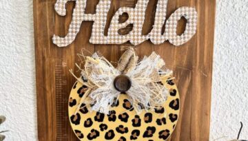 Hello leopard pumpkin DIY fall decor with a stained paint stick background, pearl bead hanger, lace and burlap bow, and scrabble tile letters.