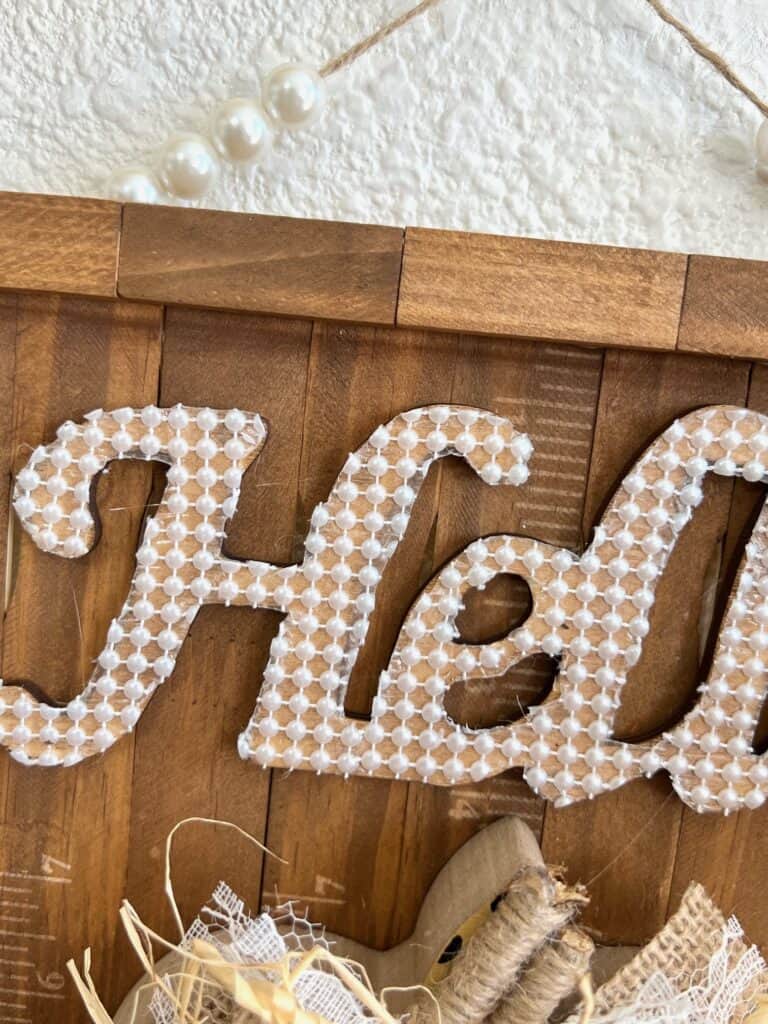 The wood cutout word "Hello" covered with pearl adhesive strip.