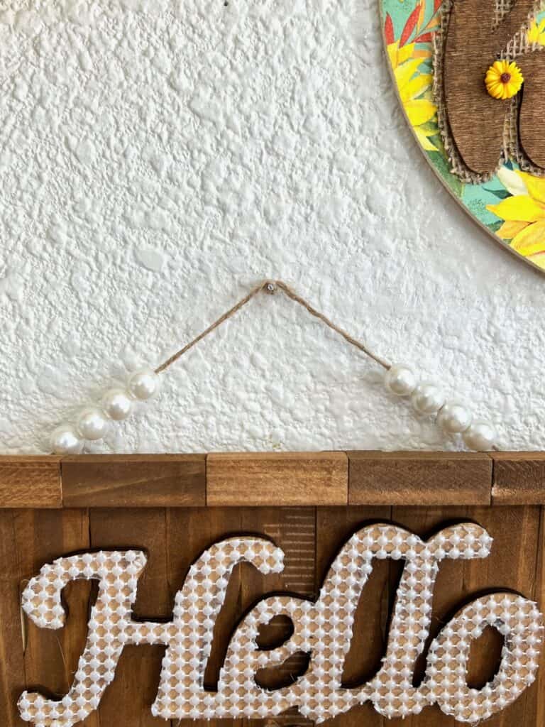 Pearl bead hanger for the sign hanging on the wall.