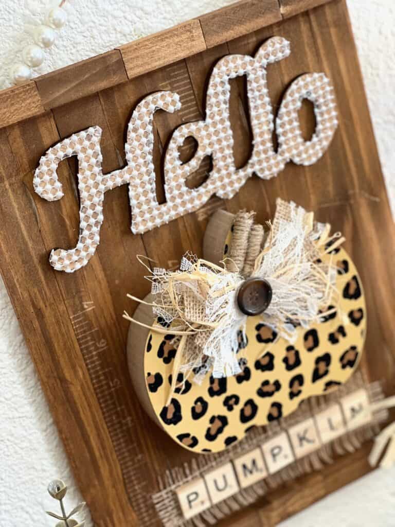 Hello leopard pumpkin DIY fall decor with a stained paint stick background, pearl bead hanger, lace and burlap bow, and  scrabble tile letters.