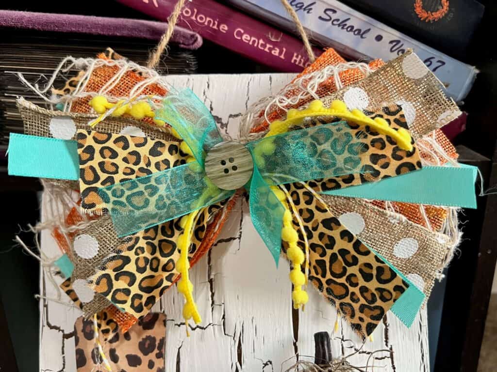 Big messy bow with yellow, orange, teal and leopard print with a button in the center.