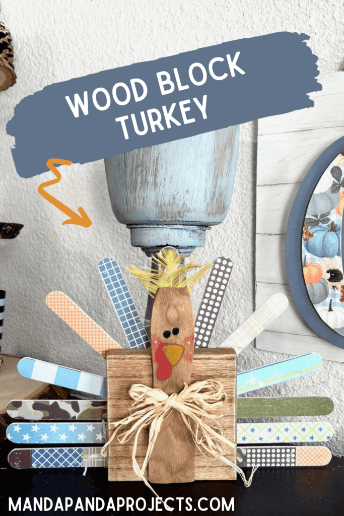 DIY Wood Block Turkey made with a 4x4 wood square, jumbo popsicle sticks, coordinating fall scrapbook paper, a raffia bow, and a cute feather, decor for your thanksgiving holiday.