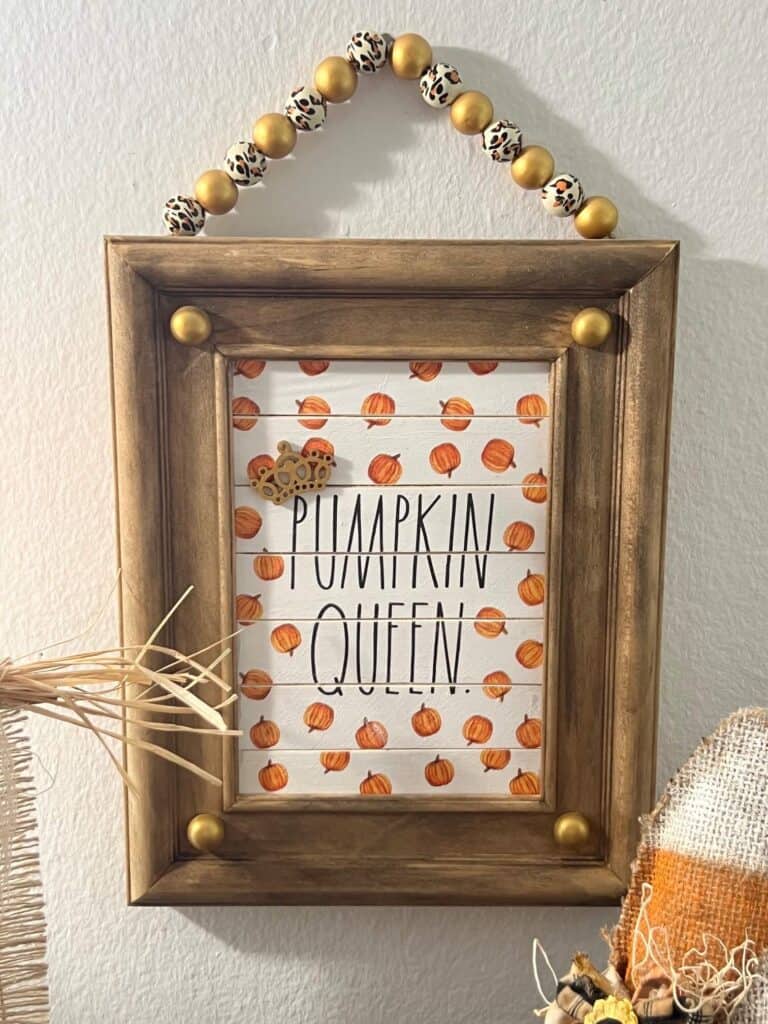 Reverse canvas with a pumpkin queen napkin in the frame and gold land leopard print wood bead hanger.