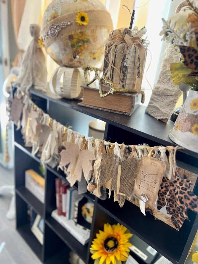 Neutral Fall-O-Ween Bookcase inspo to decorate for fall and halloween with DIY crafts and decor as well is thrift store finds with neutral, gold, leopard print, and vintage sunflower