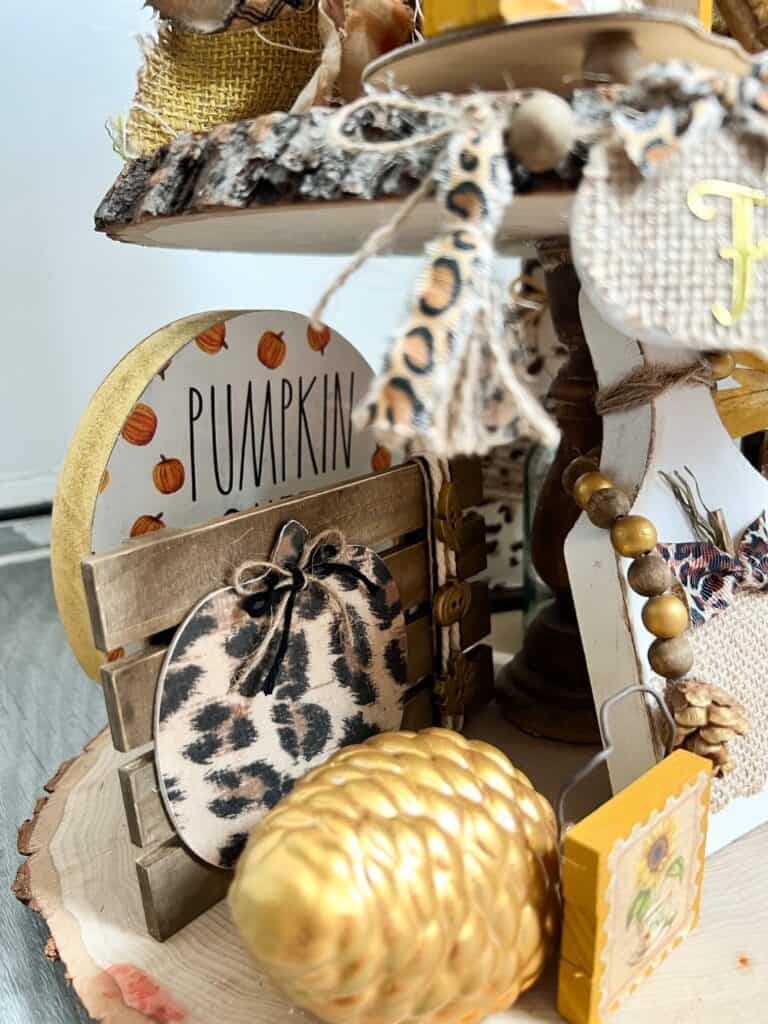 The back of the tiered tray showing the Pumpkin Queen round sitter and the leopard print pumpkin pallet, with the gold pine cone in front.