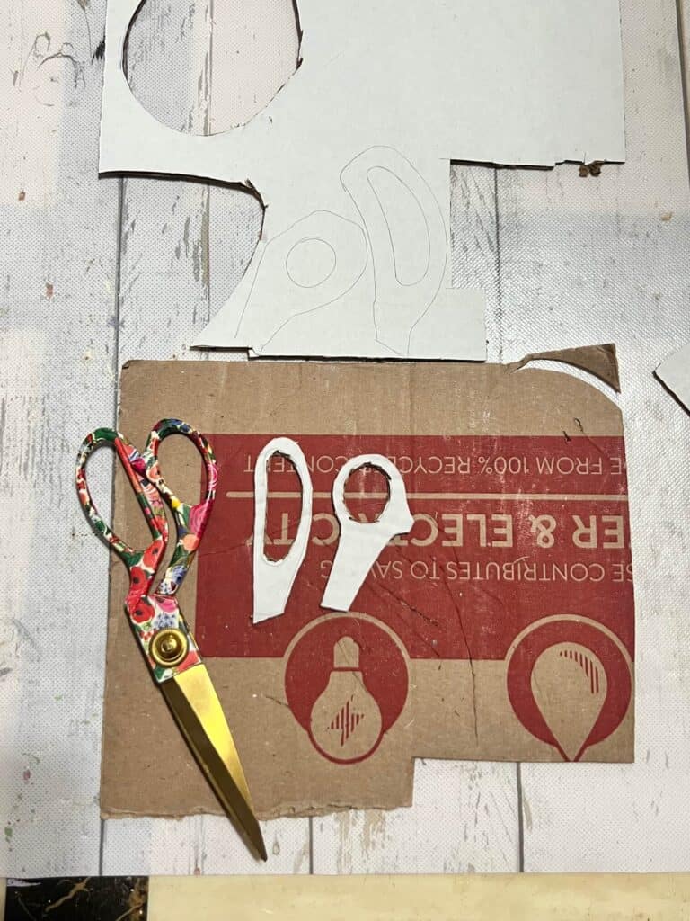 The handle of a pair of scissors traced onto cardboard and cut out