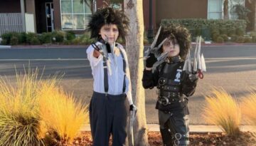 DIY Edward Scissorhands Costumes made with thrift store clothes and belts. Two different versions from the movie, one with black belted leather suit and one with grey pants, and white shirt with suspenders. Both wearing handmade scissorhands gloves and wild black wigs with scars on their faces and a pale complexion.