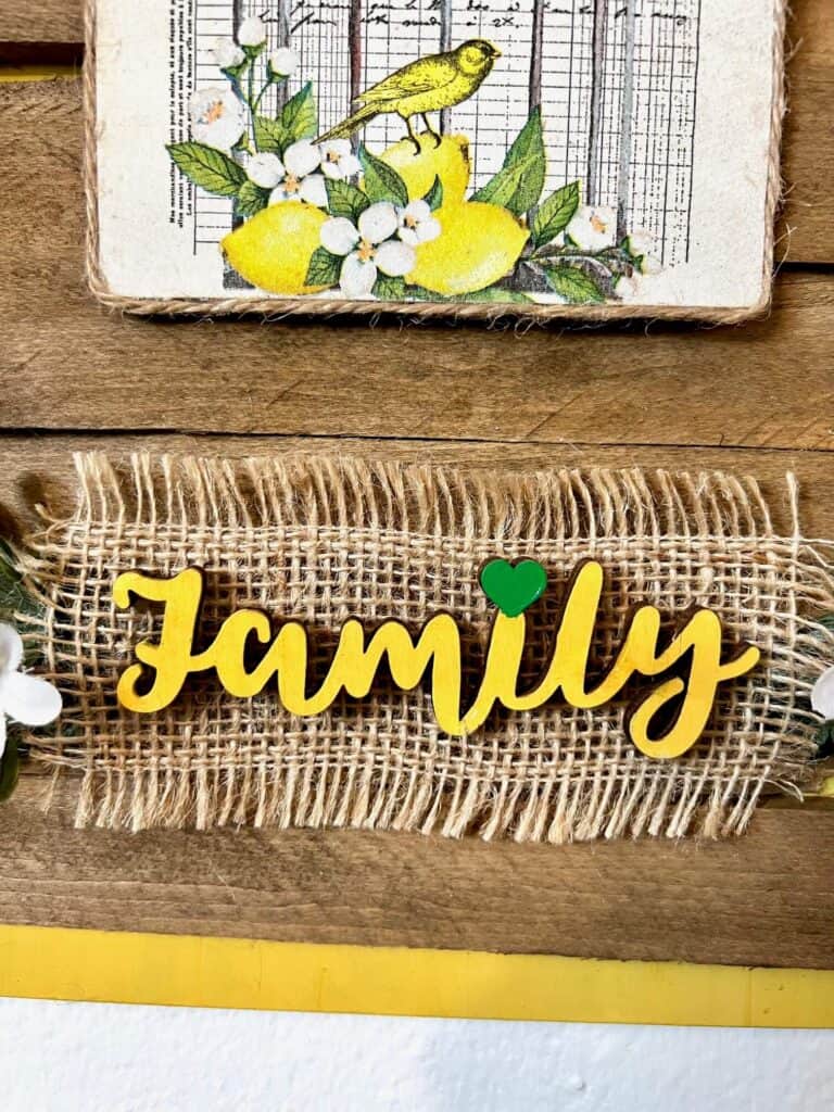 The word family painted yellow with the dot of the "I" being a small green heart instead of a dot.