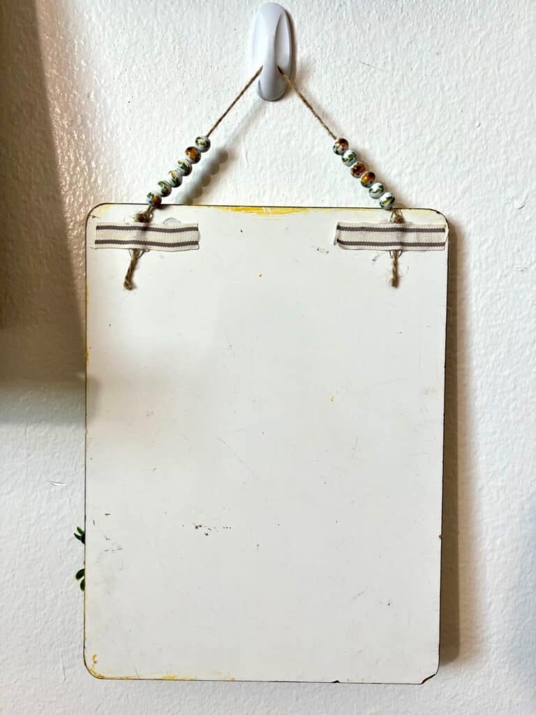 The back of the project showing the glass sunflower bead hanger glued to the top back, hanging on the wall.
