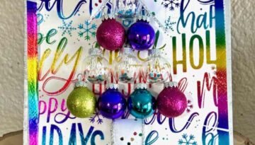 Colorful Ornament bulb Christmas Tree Frame made with a holiday rainbow color napkin with various christmas phrases on it, small round bulb ornaments in the shape of a christmas tree with a bow as the tree topper and som totally dazzled bling. Bright and cheery diy christmas decor.