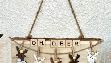 DIY Reindeer Oversized Christmas Ornament with 5 neutral tan deer, hanging from a piece of twine with mini clothespins and scrabble tile letters at the top that says "OH DEER" all on a piece of Dollar Tree natural wood plaque.