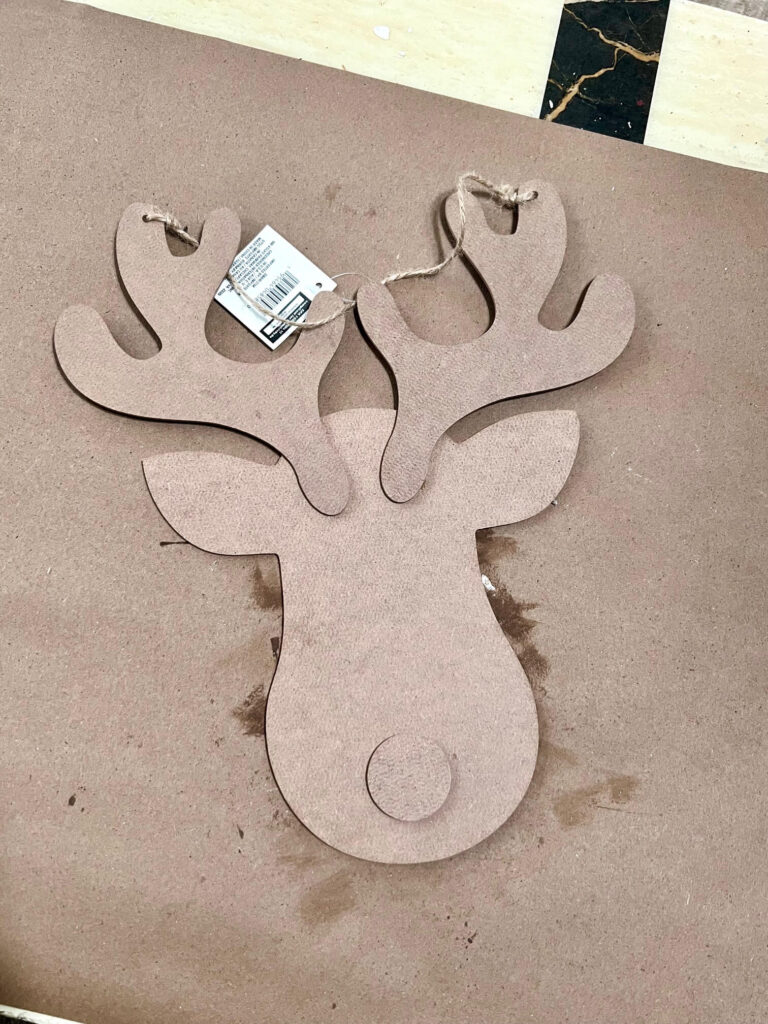 Unfinished wood rudolph the red-nosed reindeer wood cutout sitting on a table with kraft paper.