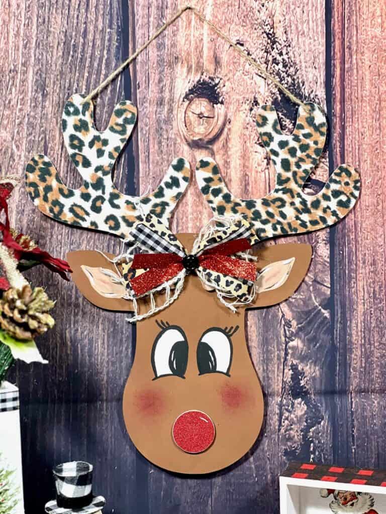 DIY Dollar Tree Wood Rudolph the Red Nosed Reindeer, with leopard print antlers, a hand painted face, and cute bow for DIY Christmas decor.