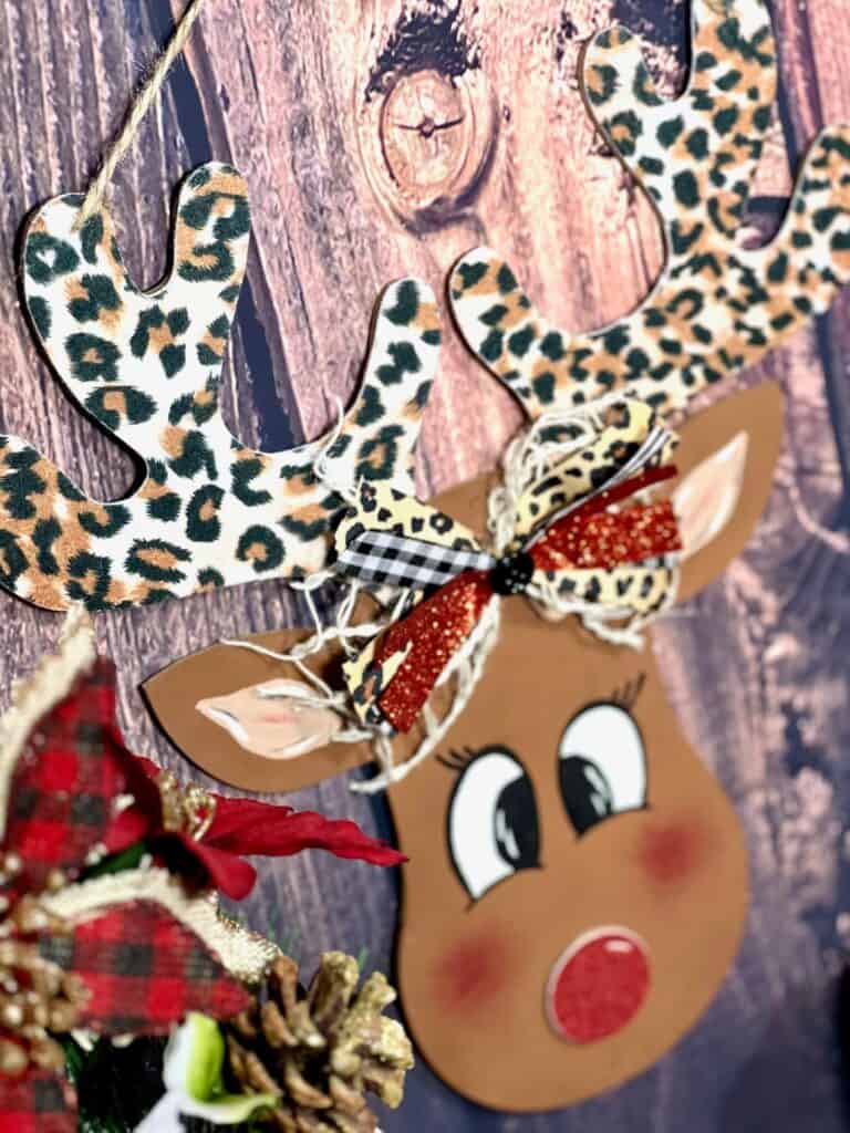 DIY Dollar Tree Wood Rudolph the Red Nosed Reindeer, with leopard print antlers, a hand painted face, and cute bow for DIY Christmas decor.