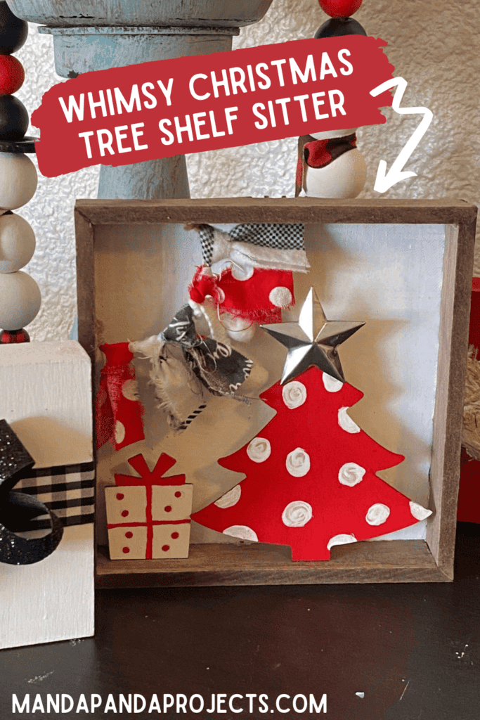 Whimsy Christmas Tree Shelf sitter that is small enough to fit on a tiered tray with a Dollar Tree wood Christmas tree painted red with white polka dots, a small wood present under the tree and a fabric garland in the top left corner. 