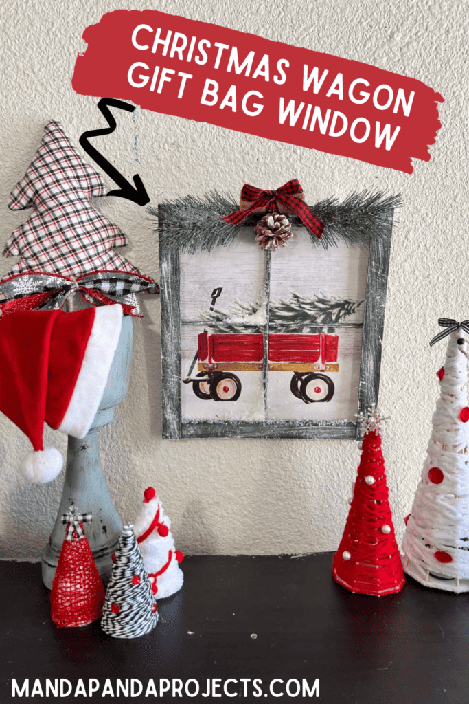 Christmas Wagon with a christmas tree in it Gift Bag Window Frame with black painted paint sticks as the frame, dry brushed with white to look like snow, faux snow, snowy greenery at the top with cinnamon sticks, a pine cone, and a black and red buffalo check bow.
