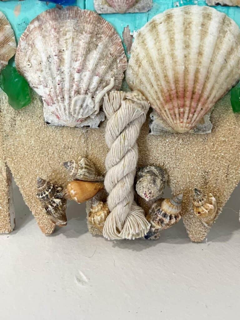 The bottom of the christmas tree with sand, seashells as "presents" and nautical rope tree trunk.
