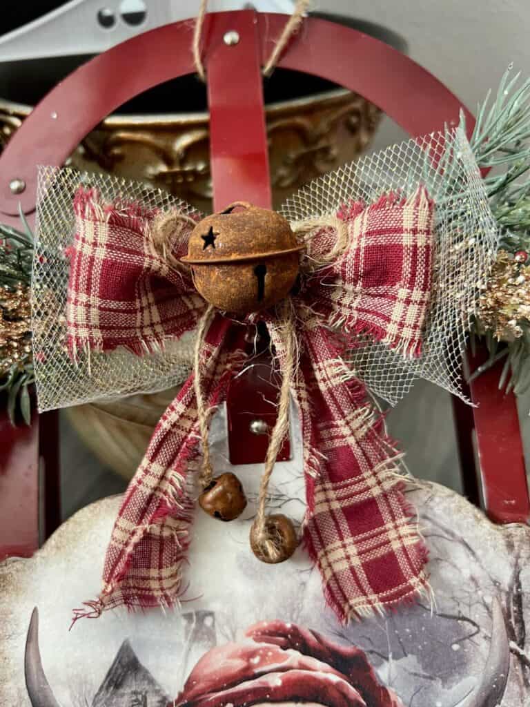 A bow with glitter tulle, red fabric, and a twine bow with rusty bells.