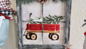 Christmas Wagon with a christmas tree in it Gift Bag Window Frame with black painted paint sticks as the frame, dry brushed with white to look like snow, faux snow, snowy greenery at the top with cinnamon sticks, a pine cone, and a black and red buffalo check bow.