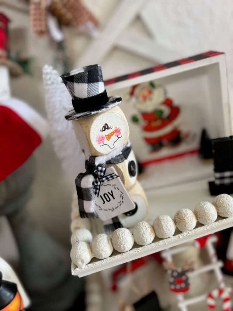 Dollar Tree Wood Block Snowman small 3 wood blocks stacked wonky with a buffalo check top hat, "Joy" hangtag, buffalo check scarf, hand painted face, perfect size for winter tiered tray decor.