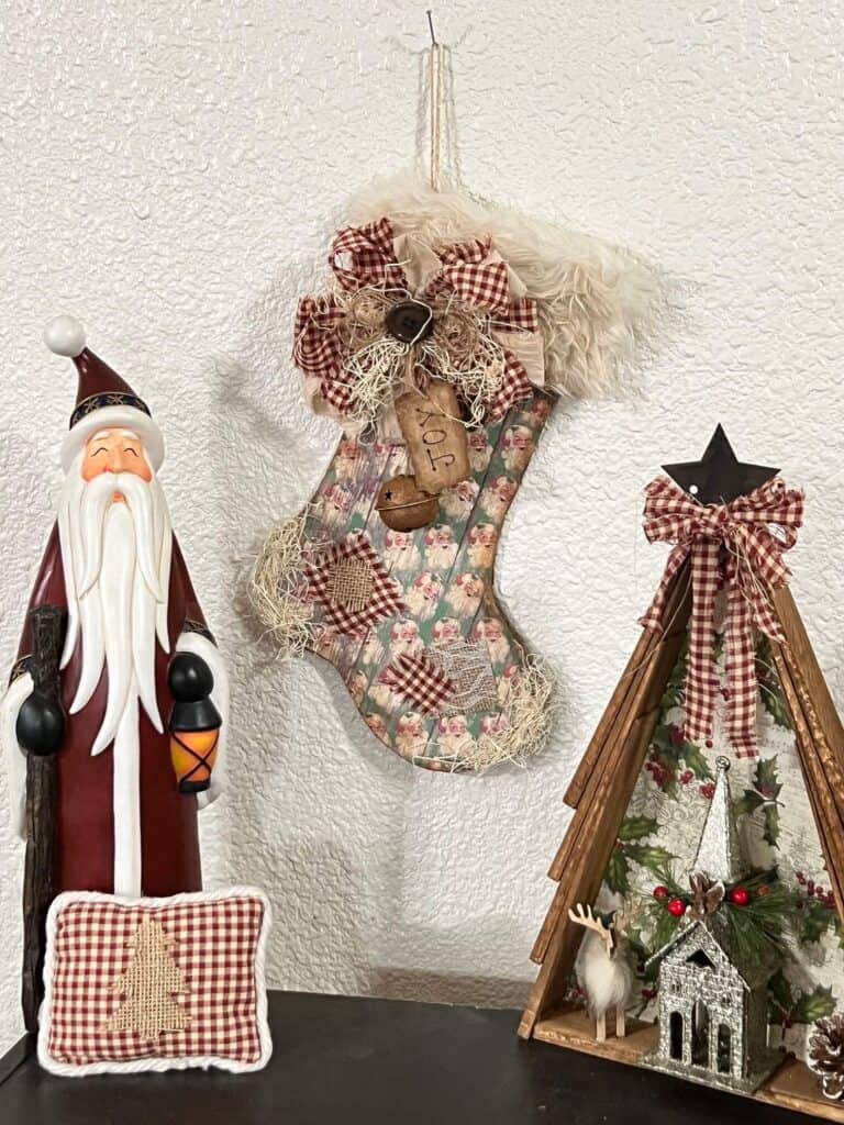 Tall ceramic santa on the left, the DIY Vintage Santa Christmas Stocking hanging on the wall in the center and a Wood Shim vintage christmas tree on the right.
