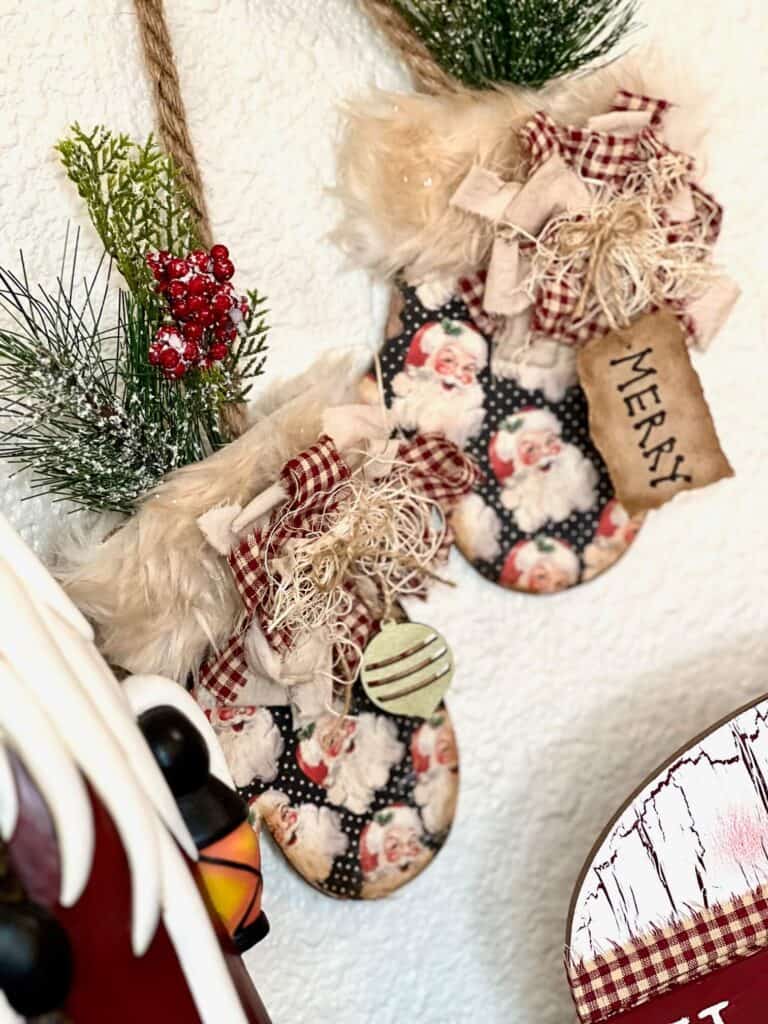 DIY Hanging Christmas Mittens with vintage santa scrapbook paper, greenery and berries, a "Merry" hangtag, and fur cuffs, DIY Christmas and winter crafts and decor.