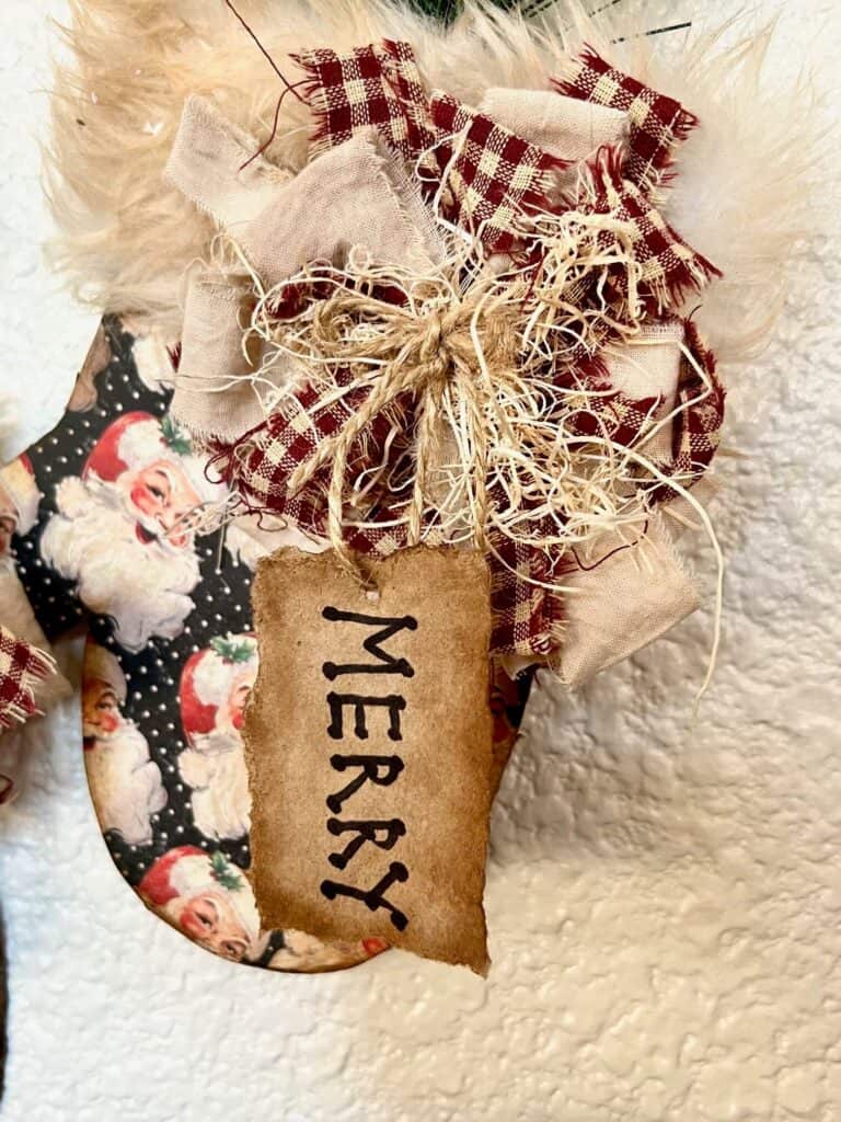 Small messy bow with excelsior and a kraft paper hangtag that says "Merry".