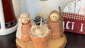 DIY Mini Terra cotta pot nativity set made with a rustic wood round, with mary, joseph, and baby jesus as natural wood beads and a mini pine cone christmas tree with a star at the top.