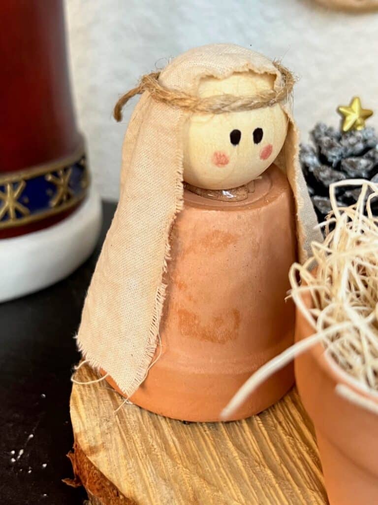 Mini terra cotta pot mary with a wood bead head and a simple hand drawn face.