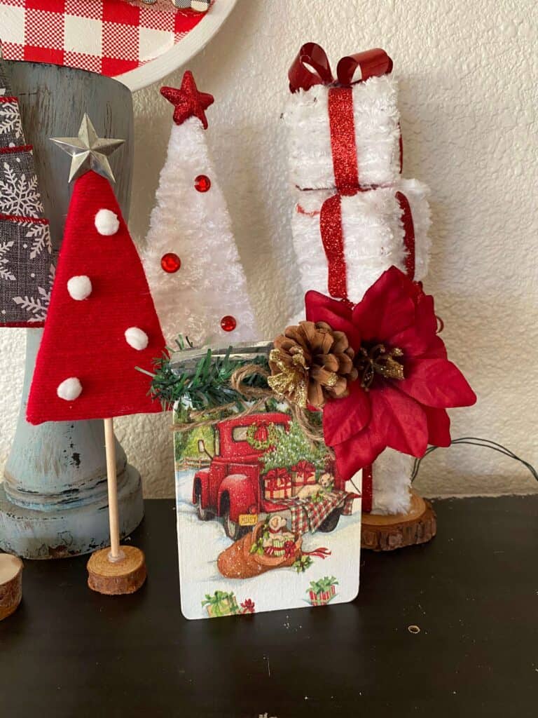 3 triangle christmas trees in the back left, the Christmas Napkin Wood Mason Jar front and center, and a white and red wonky present tower on the back right.