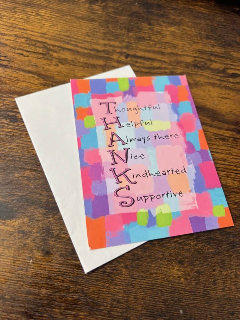 A card with an envelope sitting on a table. The card says "Thanks" written vertically with the first letter of the word thanks being another word. Thoughtful, Helpful, Always there, Nice, Kindhearted, Supportive.