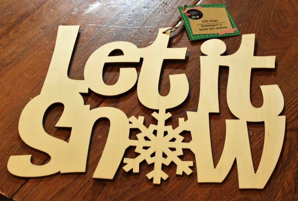 Let it Snow wood cutout sitting on a table.