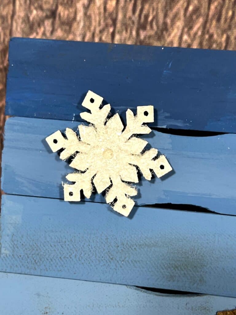 Small wooden snowflake painted white with diamond dust on top making it sparkle.
