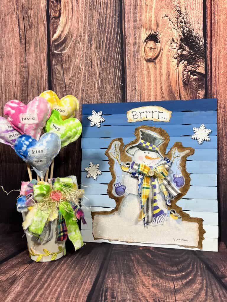 The completed snowman gift bag sign next to a bouquet of stuffed fabric hearts.