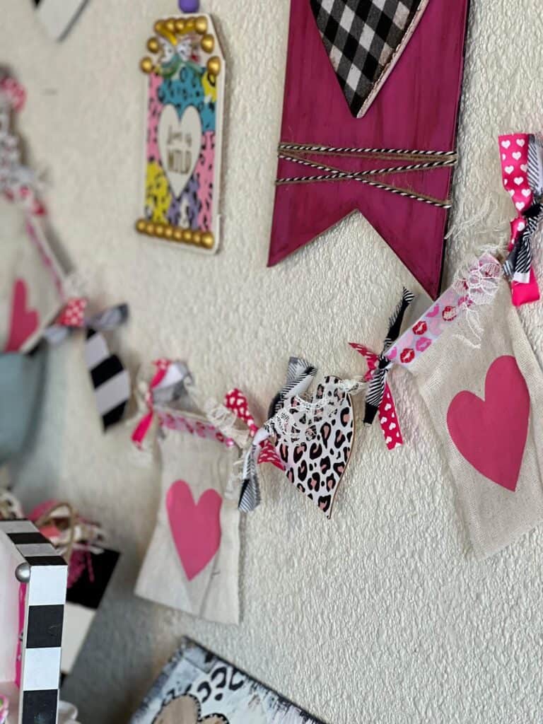 The completed valentines day banner hanging on the wall with other DIY Valentines crafts and decor.